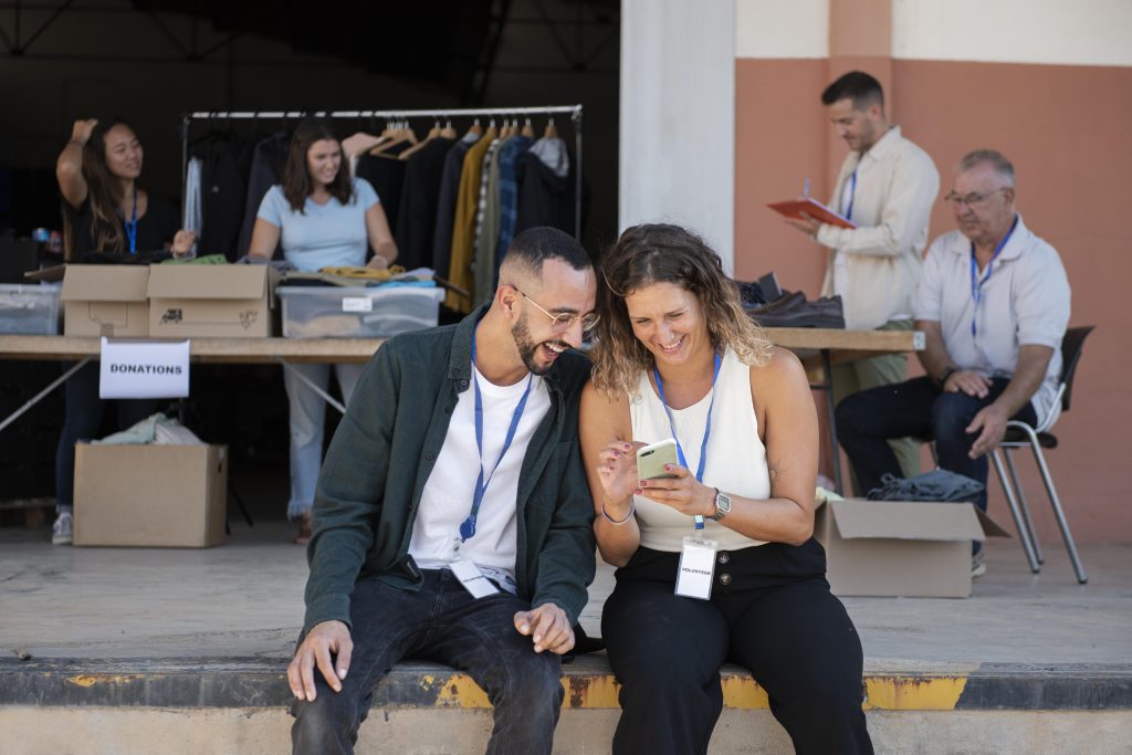 Dos jóvenes miran un móvil sentados en un banco